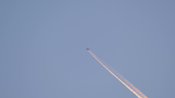 一架客机在遥远的蓝天上高空飞行，留下了白色的烟雾痕迹。航空运输概念