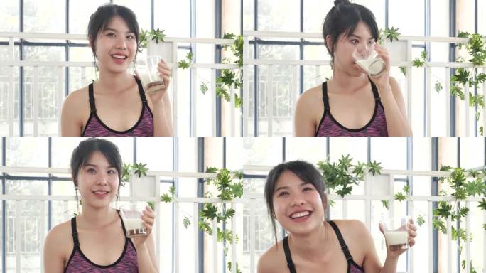 亚洲女性笑着笑着看镜头保健居家健身生活方式。美女饮用新鲜牛奶，低脂，无乳糖。女人的手拿着白色的玻璃杯