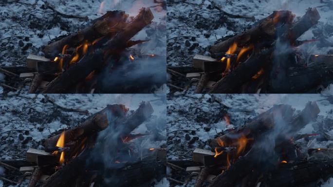 火焰特写:冬季户外场景，篝火在雪地上燃烧木头