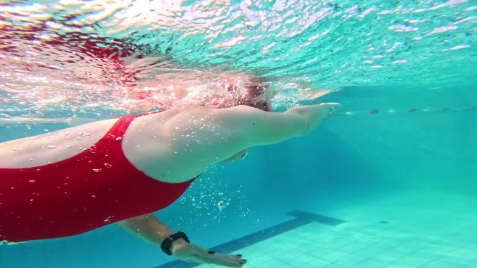 运动的年轻女子在游泳池游泳的部分水下跟踪镜头