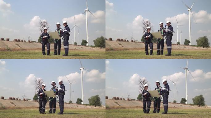 工程师男和女检查风力涡轮机农场的建设。由超级能源公司运营的带有储能系统的风力涡轮机。工人们开会检查周