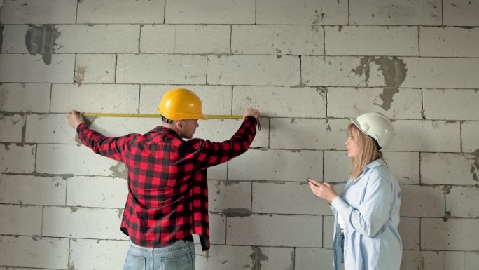 建筑专业人员在未完工住宅进行墙体测量
