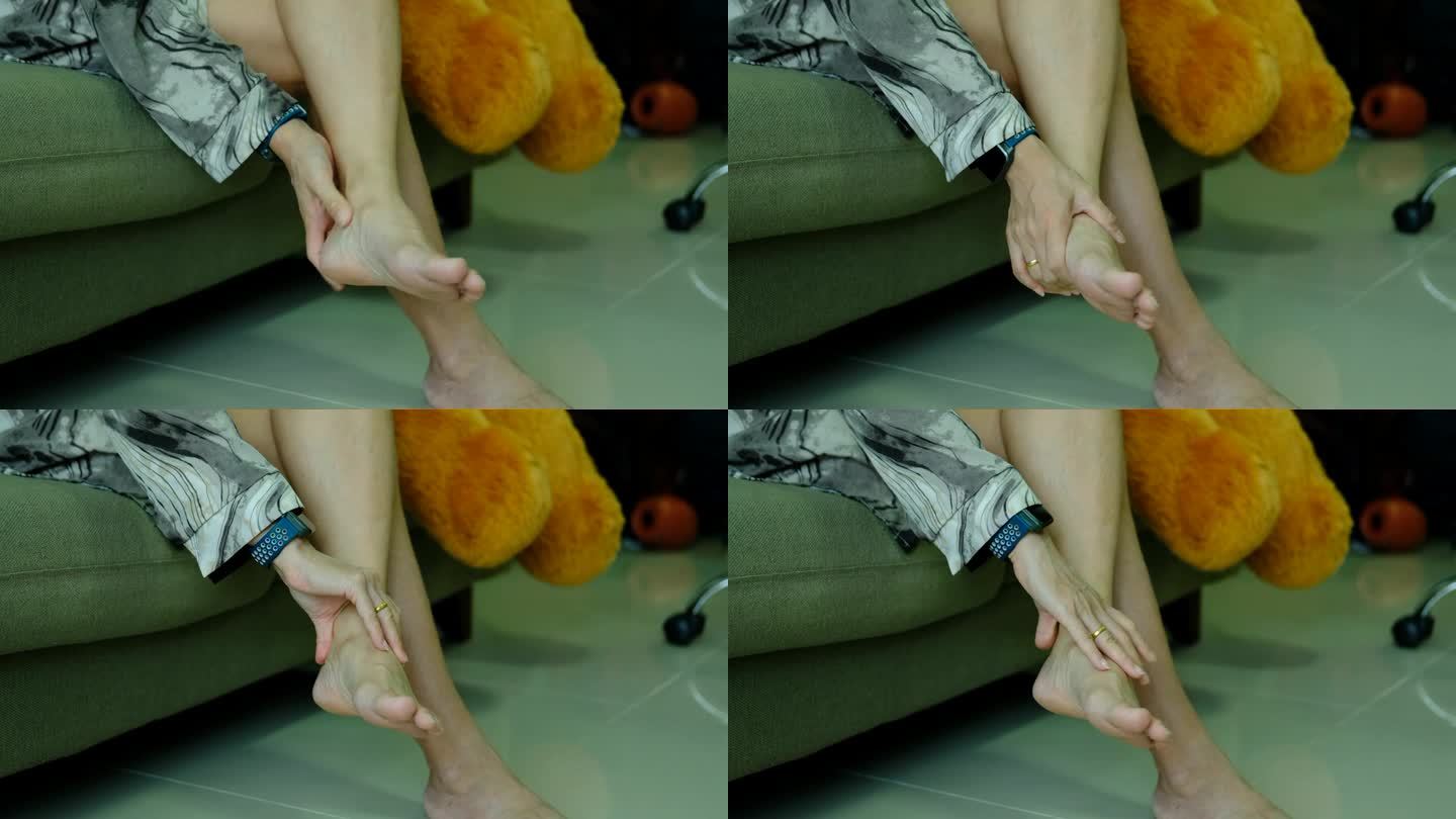 足部疼痛，亚洲女性坐在家里感觉足部疼痛，患有足部疼痛的女性用手按摩来放松脚底肌肉