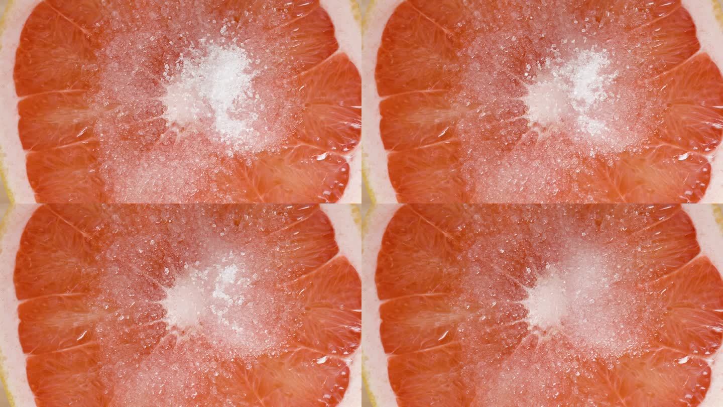 白糖晶体会很快溶解在红葡萄柚的果肉上。宏。
