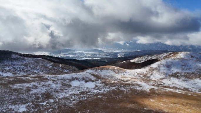 雪原高原鸟瞰图阳光明媚，但由于海拔高，云层很低，背景中可以看到城市