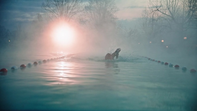 慢动作多莉拍摄的决心运动女子游泳雾蒙蒙的游泳池在旅游胜地在黎明