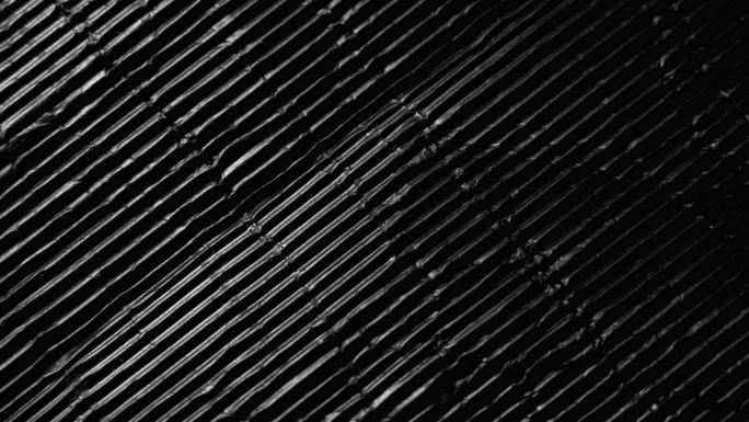 皱巴巴的黑色波纹纸，有移动的阴影和黑暗。黑色杂色抽象