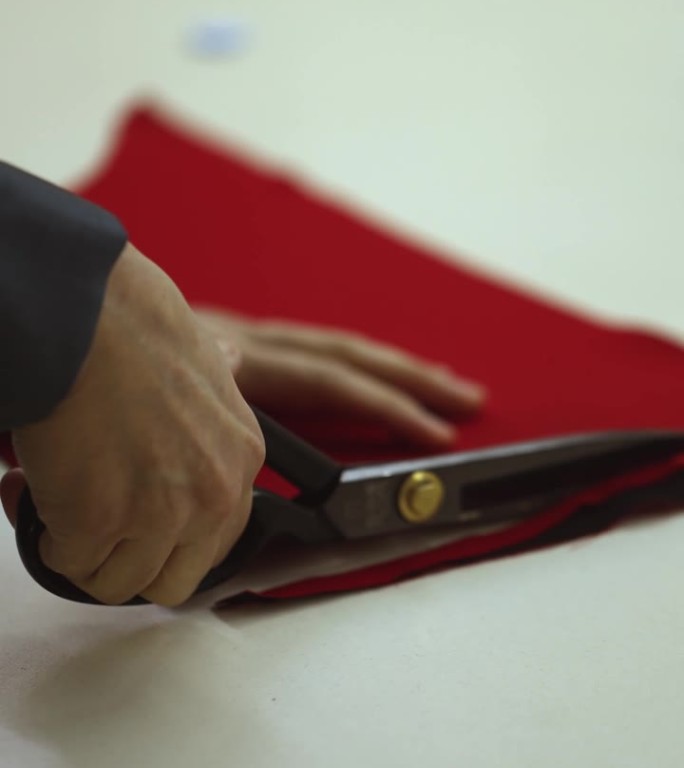 用剪刀剪红色布料。图为一名妇女用剪刀剪下一件红色连衣裙的元素。垂直视频