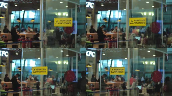 机场大楼的自动门上，一名路过的男性乘客正在吃东西