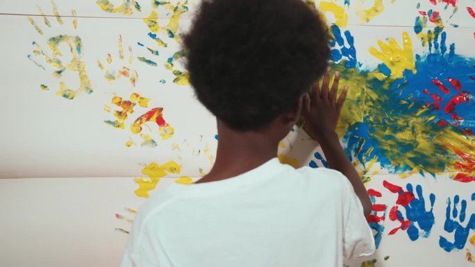 快乐的非洲男孩的后景，用手画着污迹斑斑的墙壁。启迪