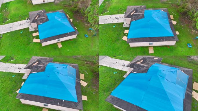 在更换沥青瓦之前，屋顶上覆盖着防水布防止雨水泄漏的俯视图。飓风伊恩袭击佛罗里达州后，建筑物屋顶受损