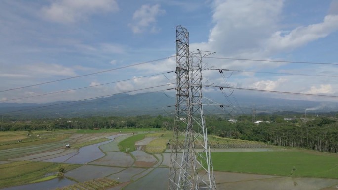 螺旋无人机拍摄的建在稻田种植中心的高压电力塔。印度尼西亚农村地区的配电设施。
