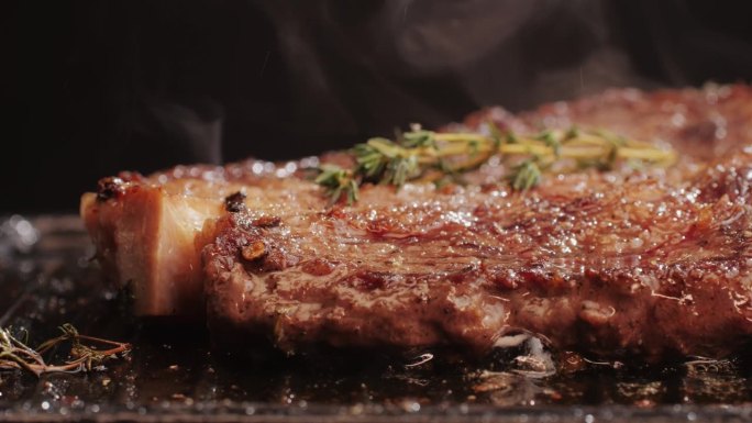 新鲜的大理石牛肉与胡椒，盐和迷迭香特写特写。在烤架上用油烹调多汁的牛排。优质有机和牛肉