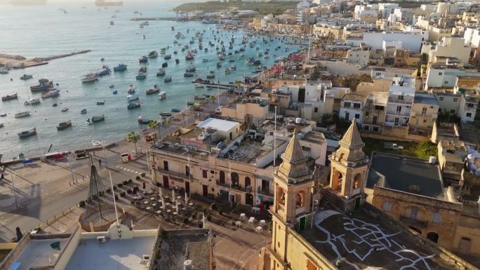 马耳他著名的渔村——马萨斯洛克。马萨克斯洛克的鸟瞰图，港口和教堂里有很多渔船。早上的超高清4K镜头