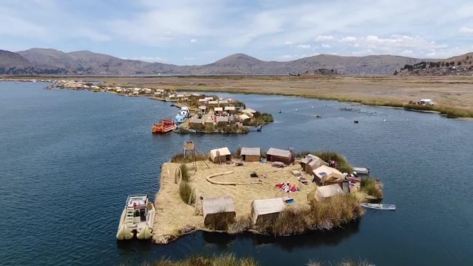 在一个阳光明媚的日子里，秘鲁的无人机鸟瞰图在普诺的提提卡卡湖的小岛上飞过huros定居点，上面有小船