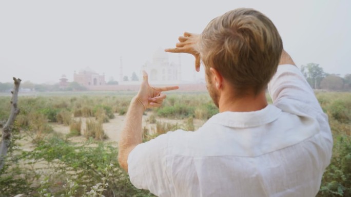 在印度旅行的年轻人用手和手指勾勒出泰姬陵的轮廓