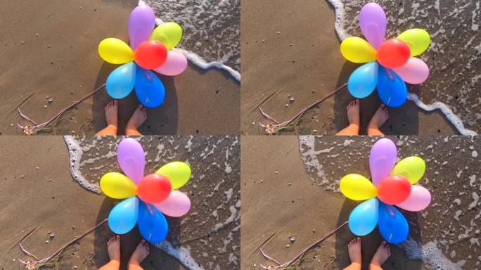 一束五颜六色的气球躺在海边的湿沙滩上，波浪翻滚，靠近一个人的脚。缓慢的运动。休闲娱乐娱乐休息娱乐庆祝