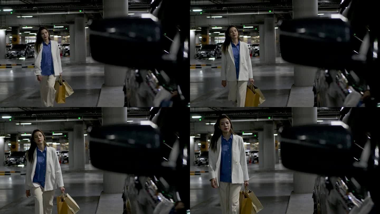 一名妇女提着一个纸袋，朝她停在一家购物中心地下室的车走去。