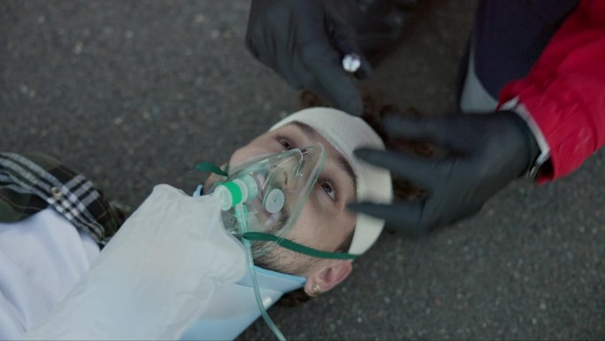 男子，护理人员，手拿手电筒，眼睛戴着氧气面罩，用于紧急情况，事故或道路医疗保健。急救人员、在街上寻求