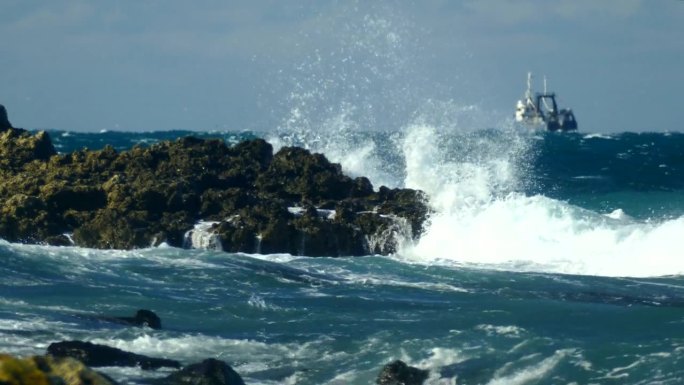 暴风雨中的渔船驶离多岩石的海岸