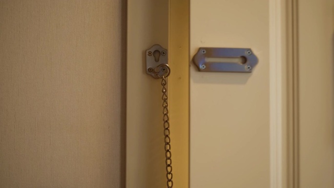 一个男人打开了锁在链子上的门锁，离开了房子