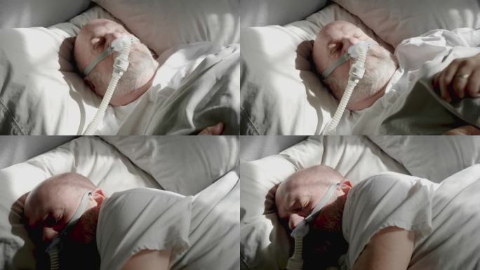 成年男子在被诊断为睡眠呼吸暂停并戴着睡眠面罩后，用CPAP(持续气道正压通气)机睡觉