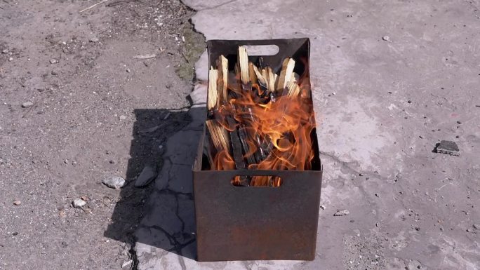 劈开的柴火在室外柴炉的烟雾中燃烧着明亮的火焰
