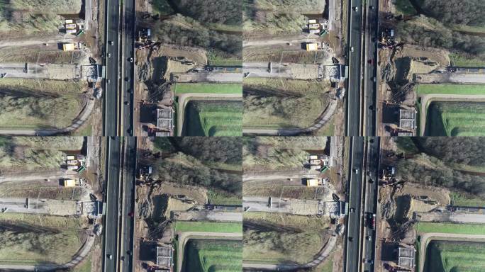 无人机从汽车和卡车行驶的高速公路上拍摄的鸟瞰图。在高速公路的左右两侧，你可以看到一个建筑工地。