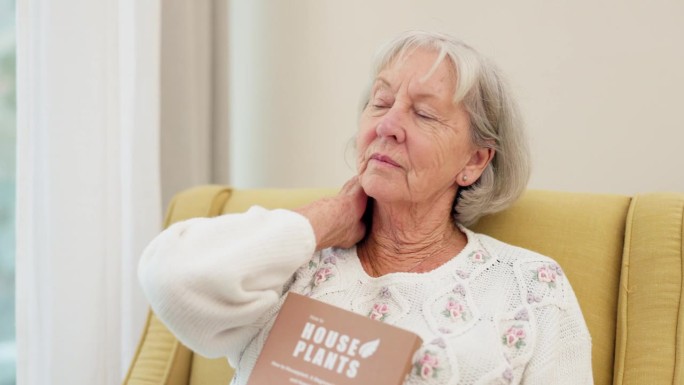 颈部疼痛、焦虑和老年女性在沙发上阅读时出现关节炎、骨质疏松或姿势问题。关节、损伤和老年女性在客厅与纤