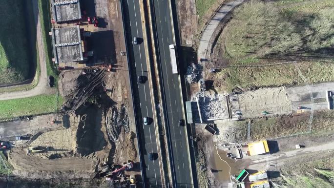 无人机从高速公路的建筑工地拍摄的。公路上有运输货物的卡车和行驶的汽车。
