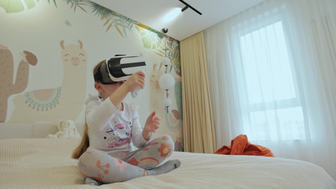 小女孩戴着虚拟现实耳机与数字世界互动，好奇的孩子用虚拟现实探索宇宙，坐在家里的床上。