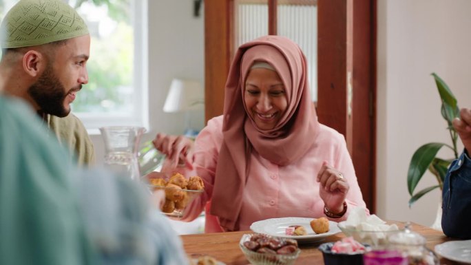 快乐的家庭，穆斯林或斋月分享食物，笑声或爱的宗教在家里的桌子。伊斯兰节日，传统和开斋一起在公寓吃清真