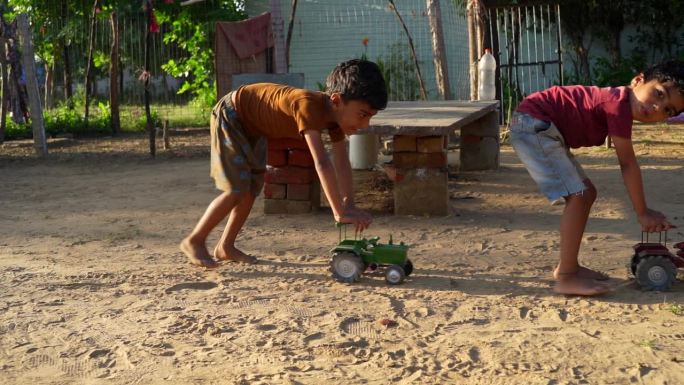 两个快乐的孩子在户外的夏日花园里玩着又大又旧的玩具拖拉机。嘻嘻哈哈的孩子们。家庭，童年，生活理念。