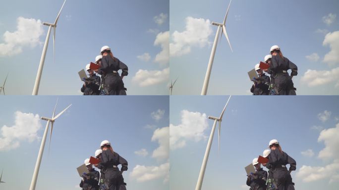 工程师男和女检查风力涡轮机农场的建设。由超级能源公司运营的带有储能系统的风力涡轮机。工人们开会检查周