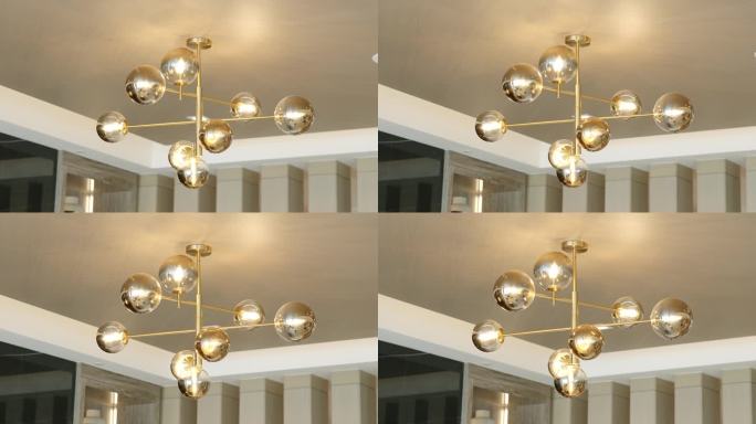 抽象的现代吊灯，圆形灯由金色金属辐条连接，悬挂在白色石膏踢脚板的吊顶上
