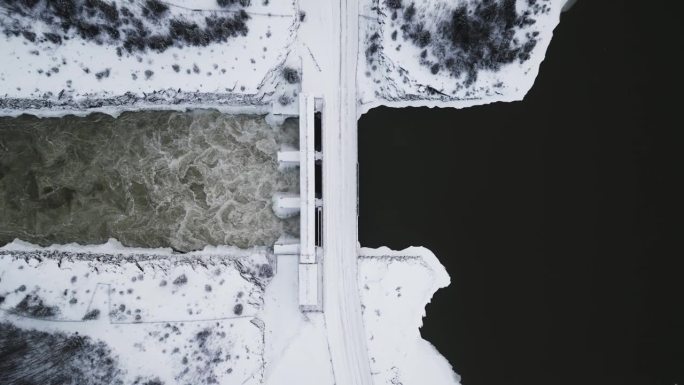 缓慢建立拍摄空中无人机视图湍急的水Notigi水电站，河流湖泊雪景北部冬季马尼托巴省加拿大