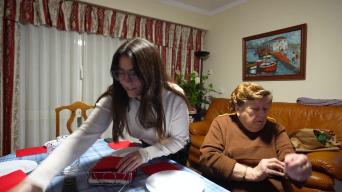 孙女在家里帮奶奶摆好餐桌，铺上红餐巾。静态