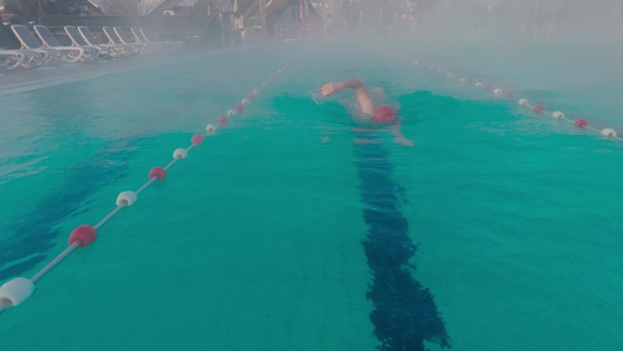 运动的年轻女子在旅游胜地雾蒙蒙的游泳池里练习自由泳的镜头