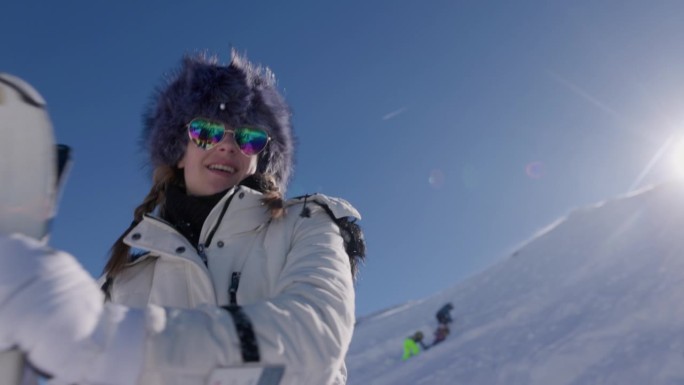 在一个阳光明媚的冬日，一名年轻女子在阿尔卑斯山的一个冰川滑雪胜地用她的滑雪板跳舞