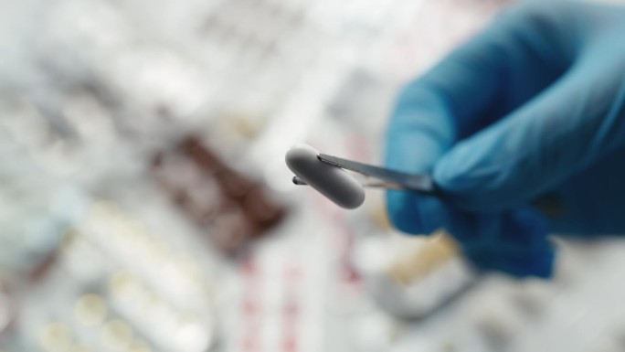 实验室工作人员用镊子拿着白色胶囊，药物发明，测试