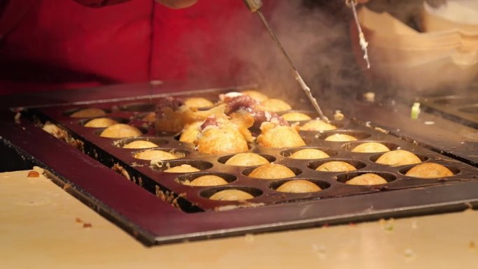 章鱼烧的制作。章鱼烧或章鱼球是夜市和步行街的一种日本食品。中国。