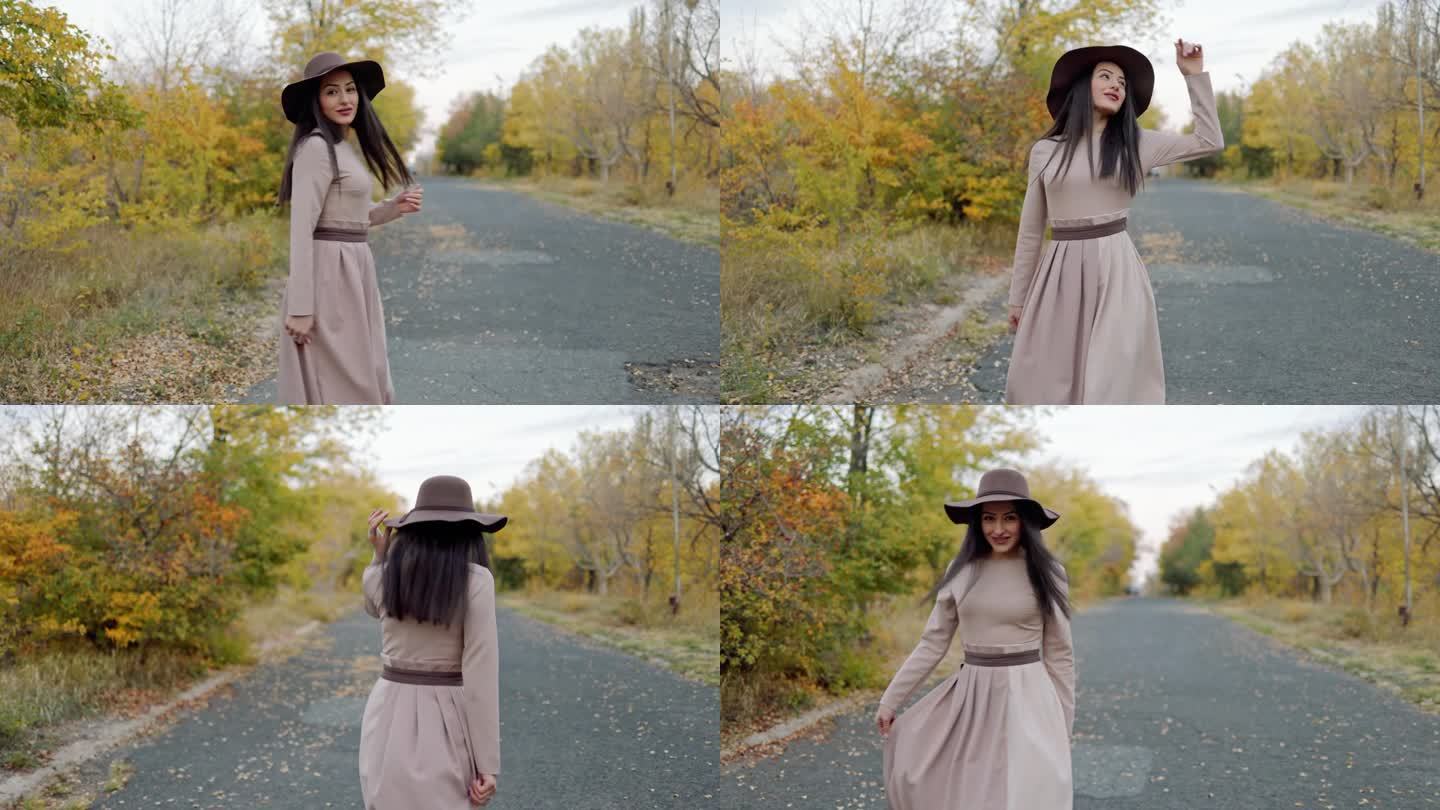 时髦的年轻女子漫步穿过公园，头上顶着帽子，带着安详的表情回头看镜头