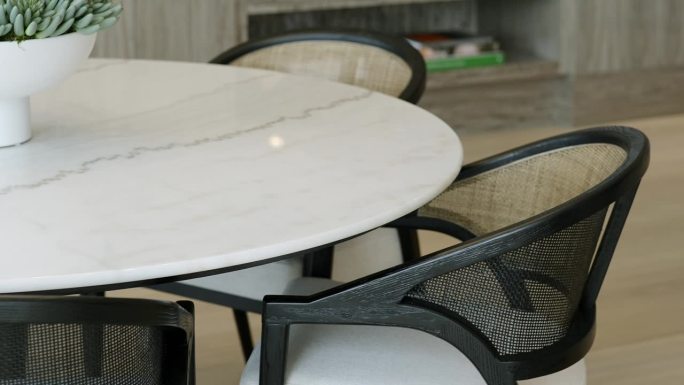 三把时尚的椅子，白色的座椅和半透明的靠背，站在咖啡桌旁边，大理石表面上有植物，室内以木地板为背景