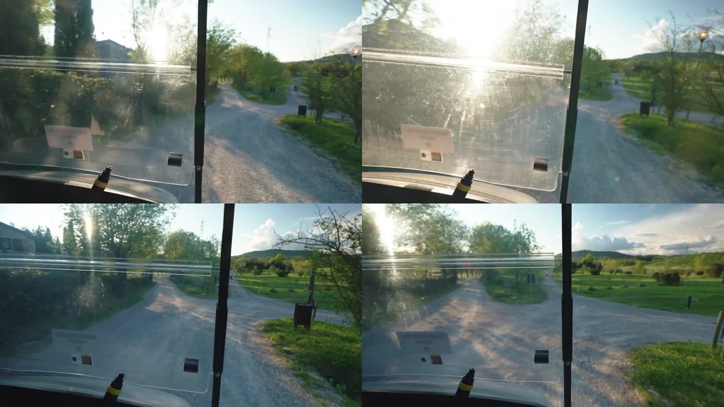 沿着高尔夫球场的道路驾驶高尔夫球车，从内部观看，跑车将球员送到比赛场地，车辆在阳光下穿过令人惊叹的午