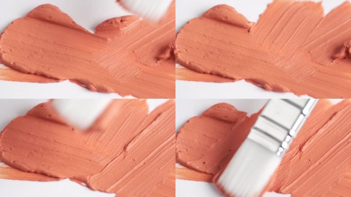 橙色粘土面膜的纹理。红色粘土面具的样品。化妆刷在白色背景上涂抹橙色面膜。