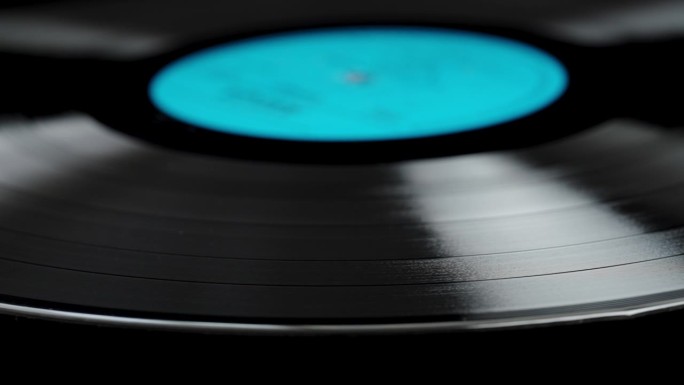 黑胶唱片的特写，蓝色标签在黑色背景上缓慢旋转。
