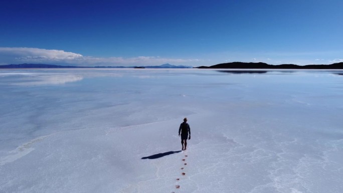 在玻利维亚的乌尤尼盐湖，一个孤独的男人在行走时留下了脚印