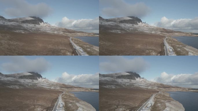 苏格兰的斯凯岛，海岸线附近，蓝天下的斯托尔老人山的雪峰和海岸线旁的一条路