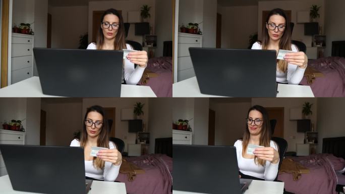 戴着眼镜的漂亮女孩拿着信用卡，在家里的笔记本电脑上网购，并成功下单