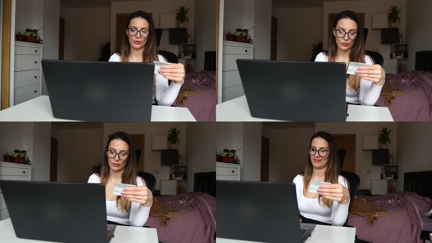戴着眼镜的漂亮女孩拿着信用卡，在家里的笔记本电脑上网购，并成功下单